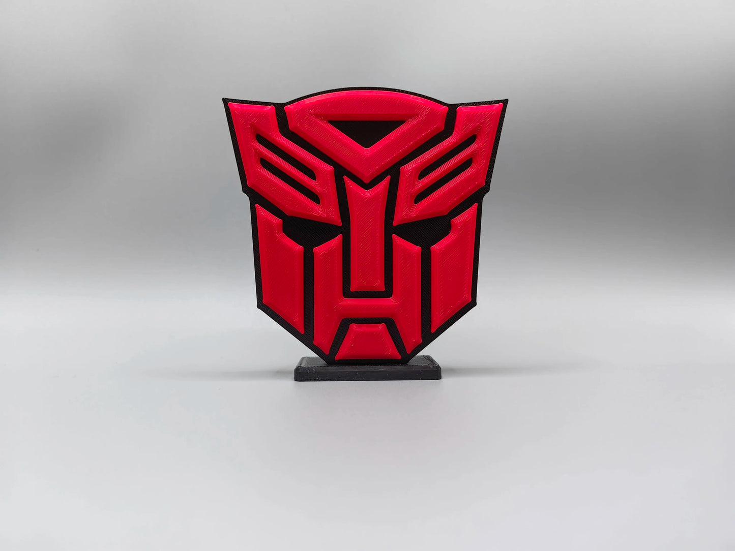 Tabliczka Transformers z intensywnie czerwonym logo Autobotów — masywna dekoracja biurka w kształcie tarczy