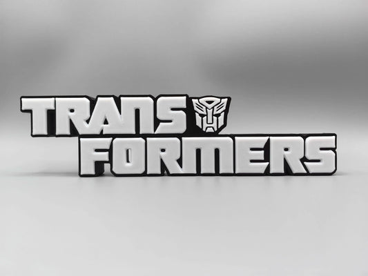 Tabliczka Transformers z monochromatycznym srebrnym logo — Metalizowana dekoracja na biurko
