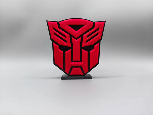 Tabliczka Transformers z intensywnie czerwonym logo Autobotów — masywna dekoracja biurka w kształcie tarczy