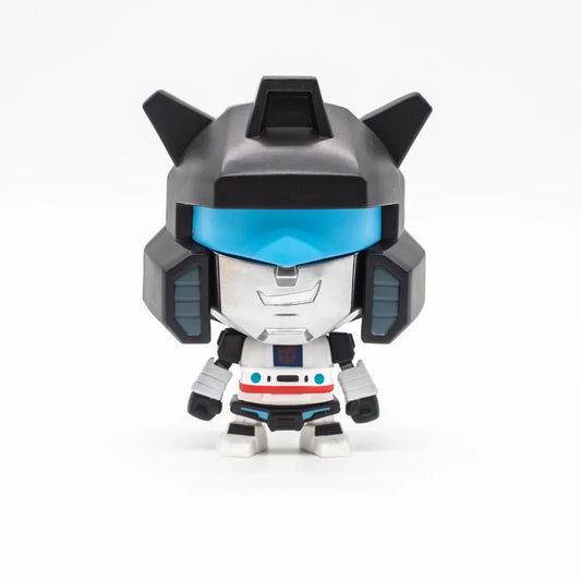 Figurine chibi robot argenté et noir, visière bleue, sur fond blanc – Transformers.